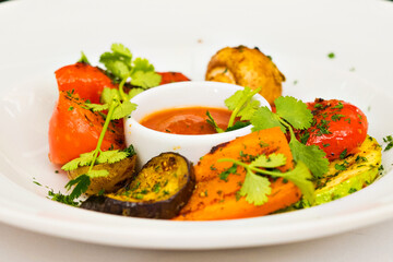 Food in a restaurant on a white plate. A man eats with a fork grilled vegetables, eggplant, karachok, zucchini, mushrooms, champignons, pepper and red sauce. High quality FullHD footage