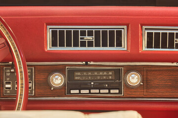 Old car radio inside a red classic American car with chrome and wooden dashboard - 566215921