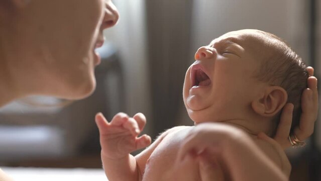 Slow Motion Shot of a Mother Holding and Talking to her New Born Baby While he Cries. Authentic Shot of a Woman New to Motherhood Trying to Sooth her Little Baby By Talking to him