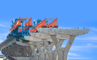 Launching gantry Structure for installing concrete Segment Joint on foundation of elevated Expressway in road Construction site against blue sky background