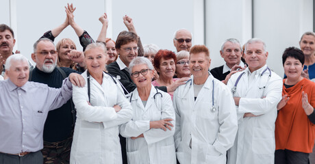 Fototapeta na wymiar Happy doctors standing in corridor with team at hospital with crossed arms looking at camera