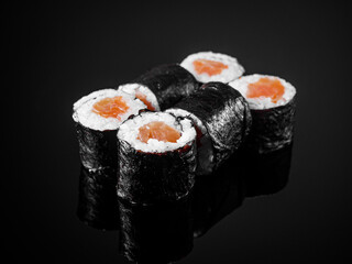 sushi roll maki with salmon on a black mirror background