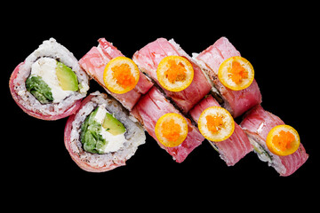 sushi roll with cream cheese, grilled tuna, cucumbers, avocado on a black mirror background