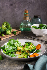 Fried broccoli, carrots and spinach leaves on a plate. Healthy food. Vertical view