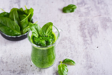Green spinach smoothie in a glass on a gray background. Healthy food.