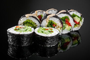 vegetarian futomaki sushi roll with cucumber, pepper, avocado salad on a black mirror background