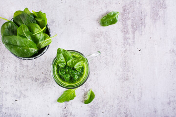 Fresh spinach smoothie in a glass and a bowl with leaves on the table. Natural antioxidant. Top view