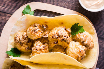 Vegetarian tacos with cauliflower and herbs on a board. Homemade food. Top view. Closeup
