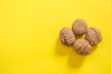 Top view of dried walnuts on yellow background with copy space