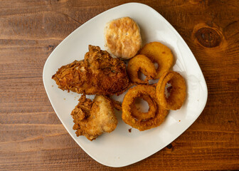 two pieces of fried chicken, onion rings and a biscuit