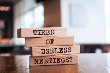 Wooden blocks with words 'Tired of Useless Meetings?'.