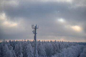 Fototapeta na wymiar Cell tower covered in frost or hoarfrost stands in a winter forest