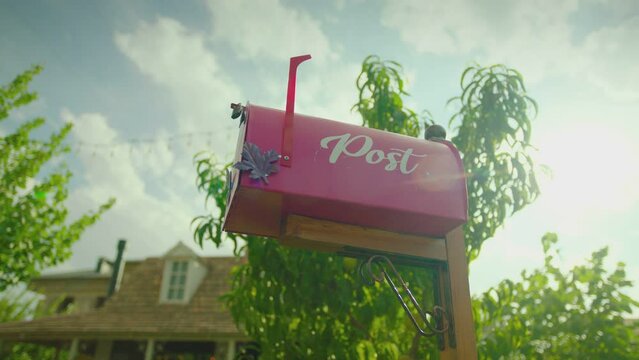 Beautiful cosy village house with trees , lawn , weathervane and mailbox . Dolly movement shot of vintage countryside home at sunny daytime . Retro designed mail box outside . Close up 