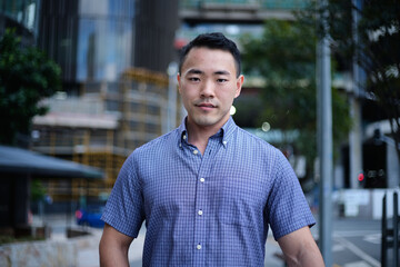 Asian man in blue shirt with city background