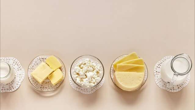 Flat lay of fresh dairy products - milk, cottage cheese, yogurt, sour cream and butter on light pastel background. Organic farm natural healthy food. Empty space for text. Top view, closeup, mock up
