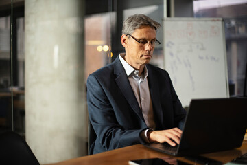 Businessman working with laptop at office. Businessman sitting at office desk working on laptop computer.