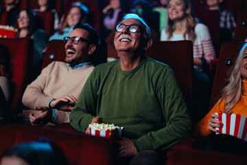 Cheerful senior watching movie in theater. - obrazy, fototapety, plakaty