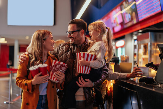 Cheerful parents with child in movie theater.