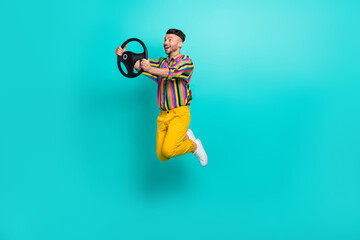 Full length cadre of funny guy wear striped shirt active jump man hold steering wheel look curious road isolated on aquamarine color background