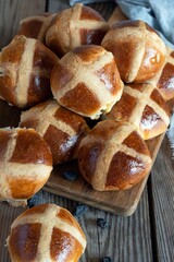 Hot cross buns with raisins, traditional English (European) pastry for Easter week on a wooden board. Delicious sweet pastries.