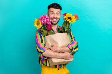 Photo of positive cheerful man hands hold bunch fresh flowers bag toothy smile isolated on teal...