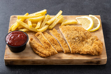 Wiener schnitzel with fried potatoes on black background