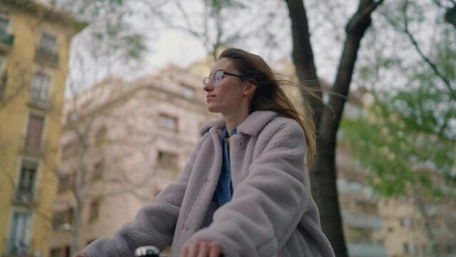 young female student having fun riding a bicycle in european city green alley. hipster attractive woman enjoying a bike ride after work on her eco friendly transport