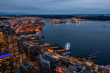 Seattle, Washington, USA - night aerial view of illuminated Seattle Downtown with skyscrapers, traffic on streets, The Great Wheel and Harbor area - aerial night view