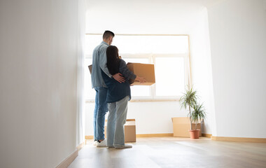 Loving Young Couple With Cardboard Boxes In Hands Standing In New Home