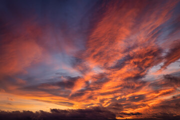 Fototapeta premium A vibrant sunset or sunrise sky with cloudscape in soft magenta, pink and orange tones as a background or texture