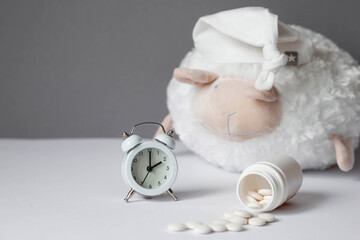 A tube of pills, a sheep in a sleep cap and an alarm clock. The time on the clock is 2 am. Insomnia and recovery of sleep mode. Count sheep to fall asleep. - obrazy, fototapety, plakaty