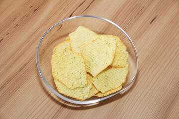 Yellow baked corrugated potato chips in a transparent plate
