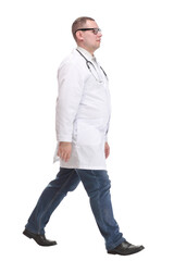 Fototapeta premium Male doctor walking isolated over a white background looking at camera -side view