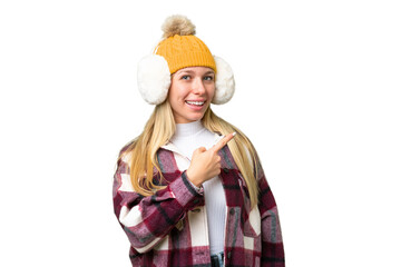 Young pretty blonde woman wearing winter muffs over isolated chroma key background pointing to the...