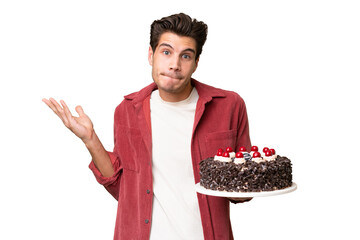 Young caucasian man holding birthday cake over isolated background having doubts while raising hands