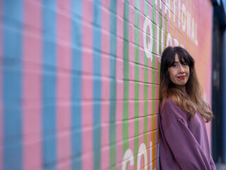 Portrait of smiling woman against colorful brick wall