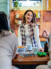 Female friends talking and eating in kitchen