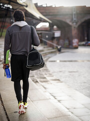Rear view of athletic man with gym bag walking outdoors - obrazy, fototapety, plakaty