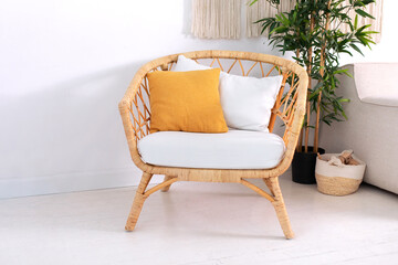 Design wicker chair in stylish light bedroom interior. Rattan armchair by the white wall in the...