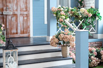 Spring design home with plants and bloom flowers hydrangea in pot on steps. House entrance...