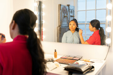 Woman getting make up in front of mirror at spa