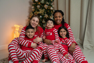 Portrait of moms with kids sitting by Christmas tree at home