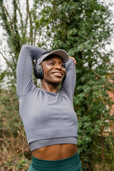 Smiling athletic woman stretching arm in park