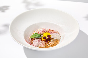 Creative creamy risotto with eel and cheese espuma. Fish risotto on white plate with unagi sauce and eel in summer menu Italian risotto from chef with smoked eel and spinach with shadows of leaves