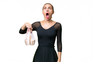 Young caucasian woman practicing ballet over isolated background looking up and with surprised expression