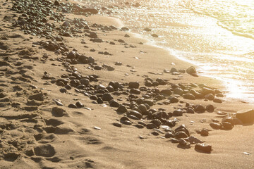 Pebbles on the beach in the rays of the setting sun. Background on the theme of romantic journeys.
