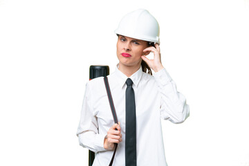 Young architect woman with helmet and holding blueprints over isolated background having doubts