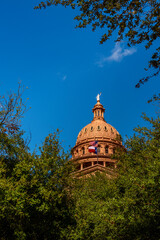 Texas State Capitol Building in Austin, the sunset red granite rooftop illuminated by the sunrays over the liveoak trees against the blue sky