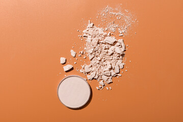 Crushed face powder heap and round box of pressed one on brown background