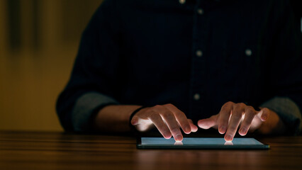 Cropped of man using digital tablet in dark office